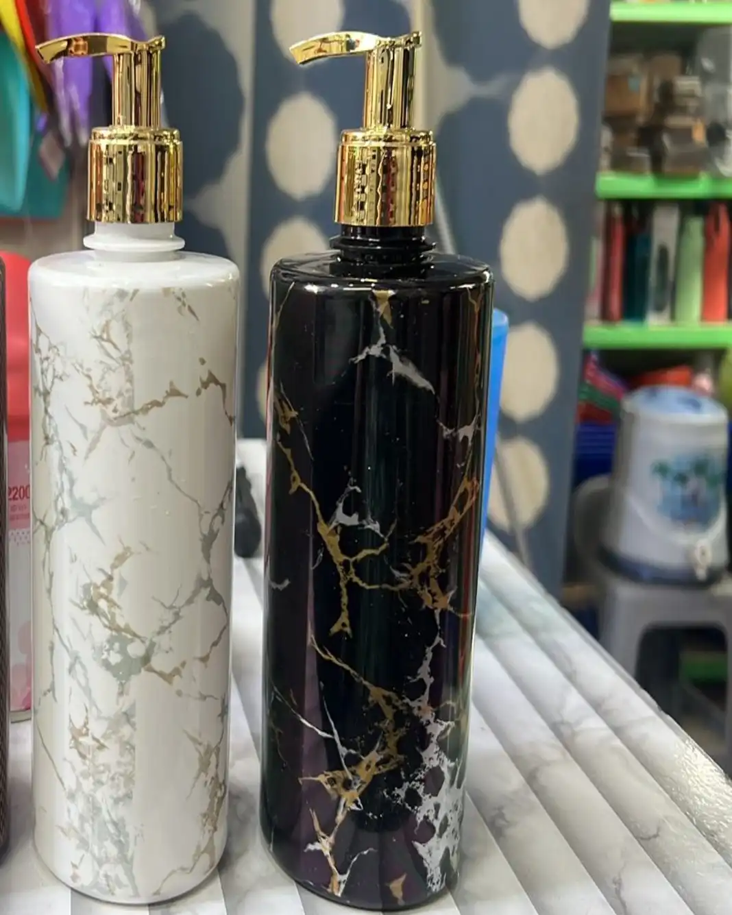 Two pump bottles, one white marble and one black marble with gold veining