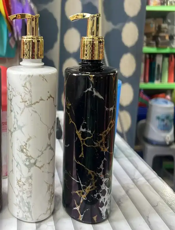 Two pump bottles, one white marble and one black marble with gold veining
