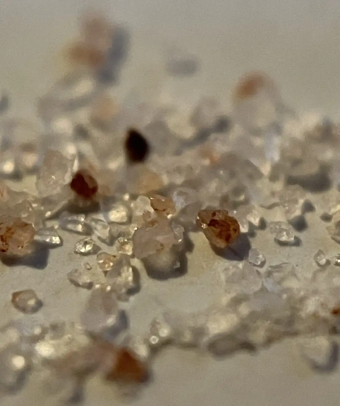 Coarse clear salt crystals with a few amber grains, close up