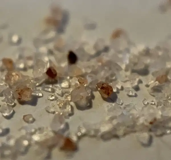 Coarse clear salt crystals with a few amber grains, close up